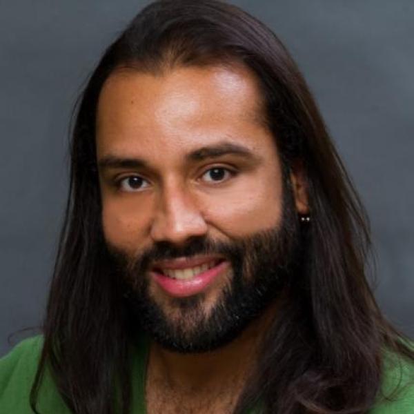 Man with long, dark hair and a green sweater
