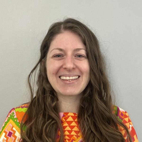 Woman with long brown hair, multicolored shirt