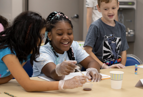 3 youth work together to pipette a liquid into a cup