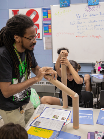 A man with long black hair models a knee with a long bending brown tube