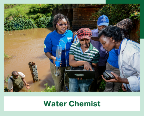 Five people stand at the edge of a river, gathered around a person holding a laptop computer. At the bottom of the image is a banner reading Water Chemist.